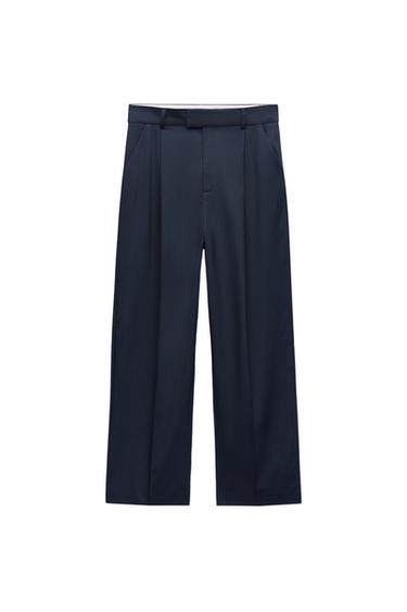 Front view of dark blue pants with pleats and side pockets.