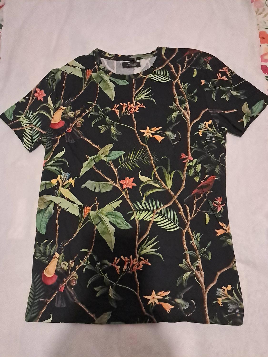 Black short-sleeved T-shirt with a botanical print of branches, leaves, flowers and birds on a white background. ZARA MAN text.