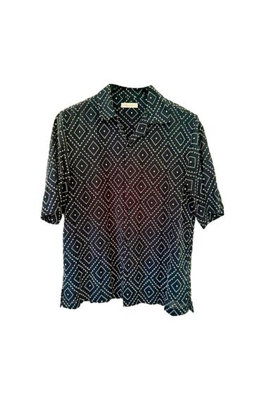 Dark, short-sleeved, button-down shirt with a white geometric diamond and dot pattern, in a relaxed style on a white background.