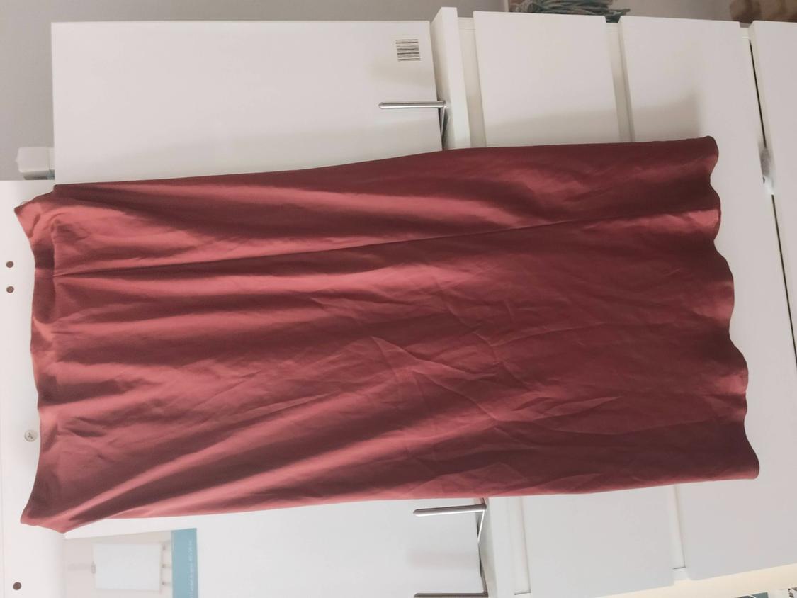 Burgundy crinkled skirt spread over a white chest of drawers. Casual and relaxed composition.