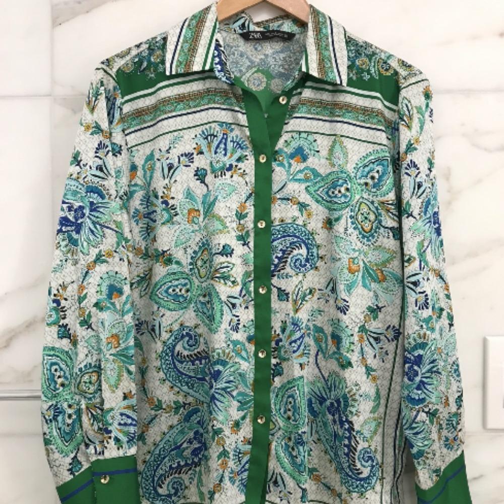ZARA long-sleeve shirt with a paisley print in green, blue, and white tones, with front buttons and a classic collar, hanging on a hanger.