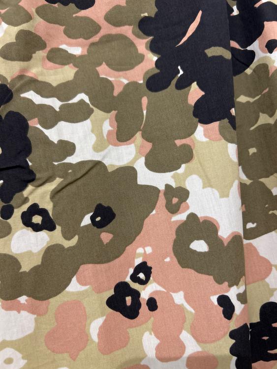 Fabric with abstract print in olive green, pink, and black tones, with irregular shapes on a light background.
