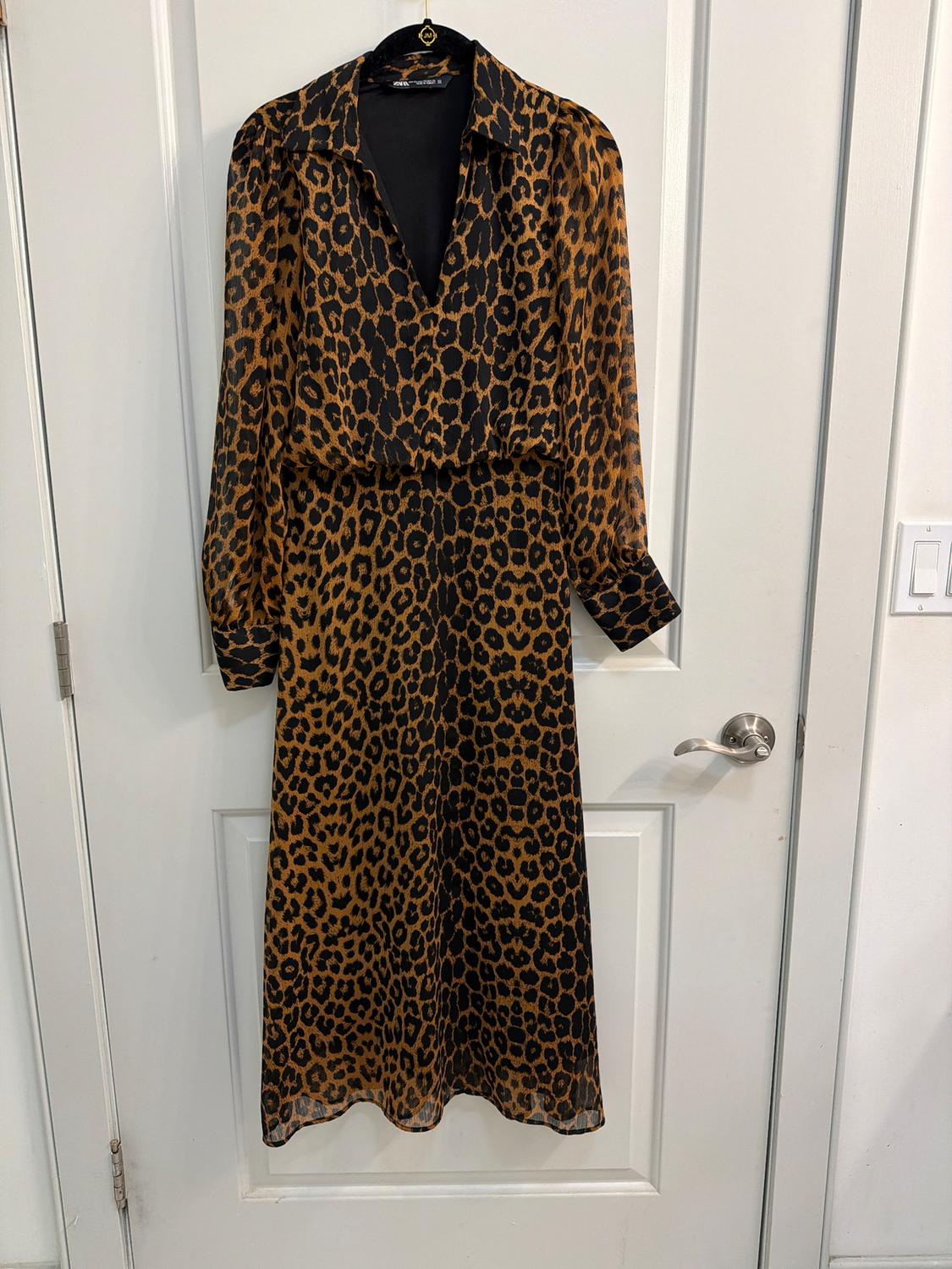 Long animal print dress in brown and black tones, hanging on a white door.