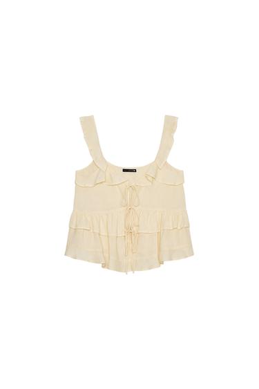 Front view of a light yellow top with frills, wide straps and a tie-front fastening.