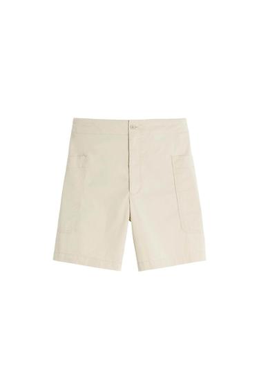 Beige shorts with large front pockets, button and zip fastening, on a white background.