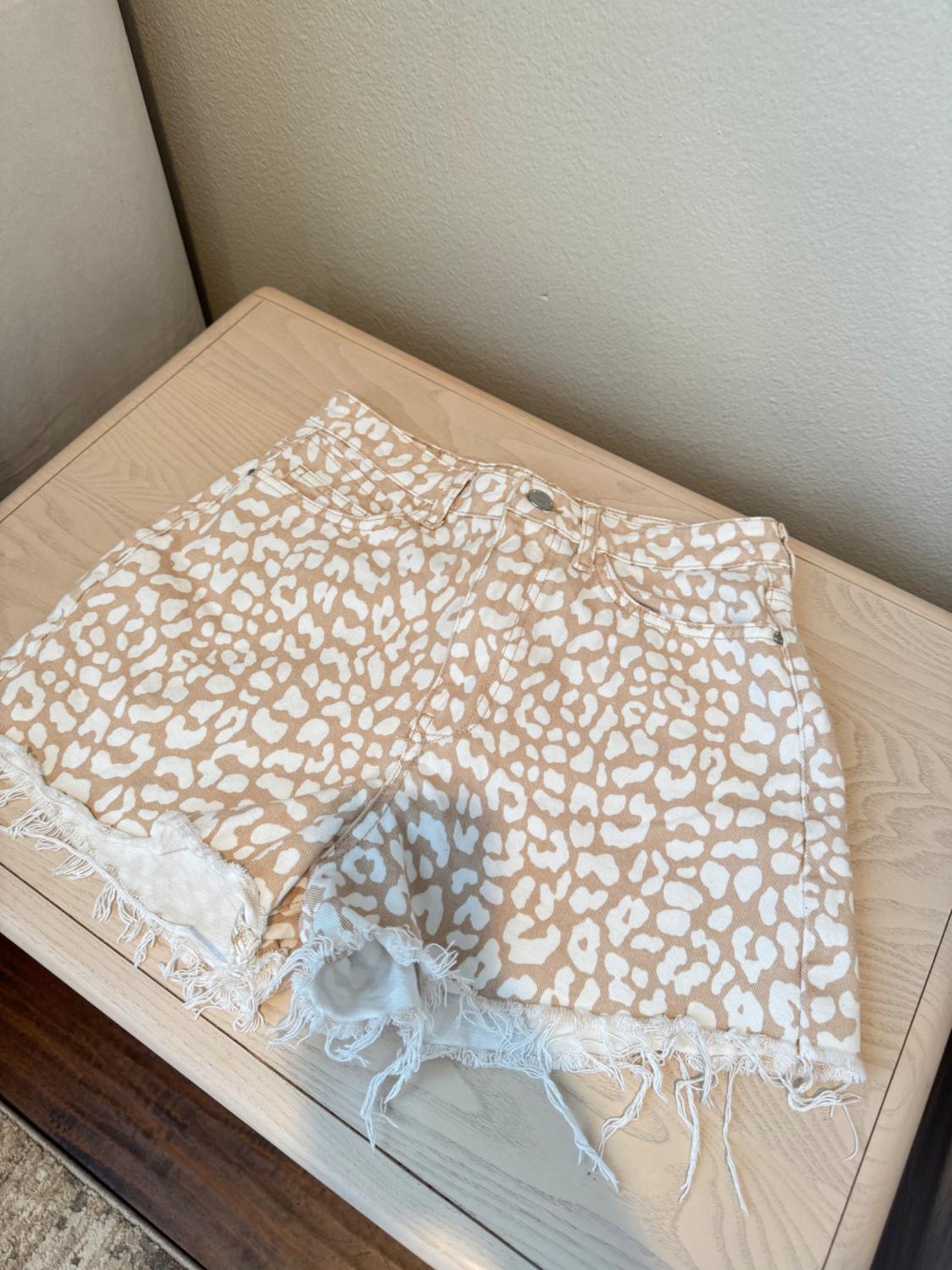 Top view of beige and white patterned shorts with frayed hems and front pockets.