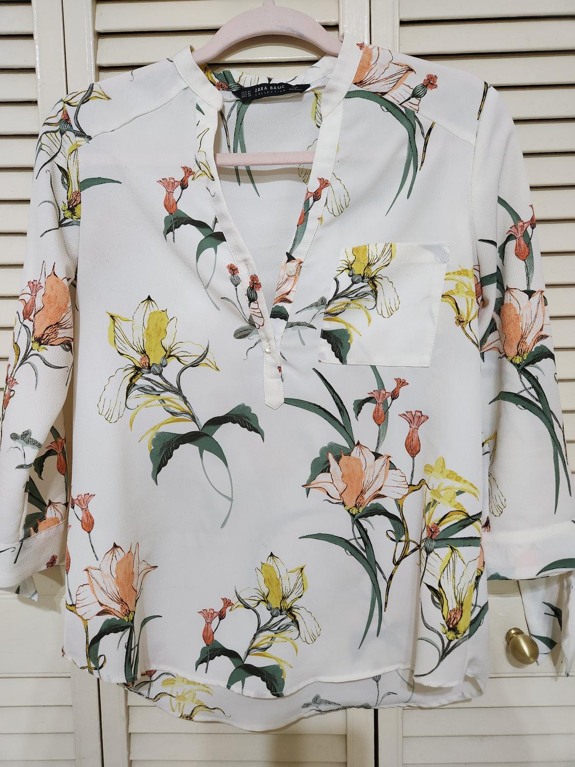 Front view of white blouse with multicolor floral print and front pocket.