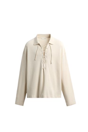 Front view of a polo shirt with a lapel collar and adjustable front opening with a drawstring. Long sleeves.