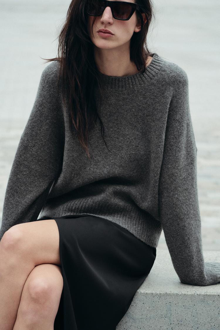 A woman wearing a gray sweater