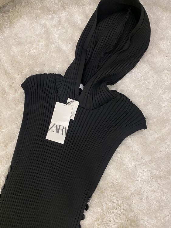 Black ribbed hoodie on a white rug. Visible label with the text "ZARA".