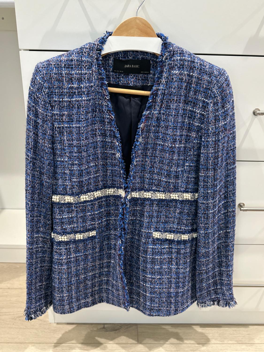 Front view of textured blue jacket, front pockets with white trim, no visible buttons.
