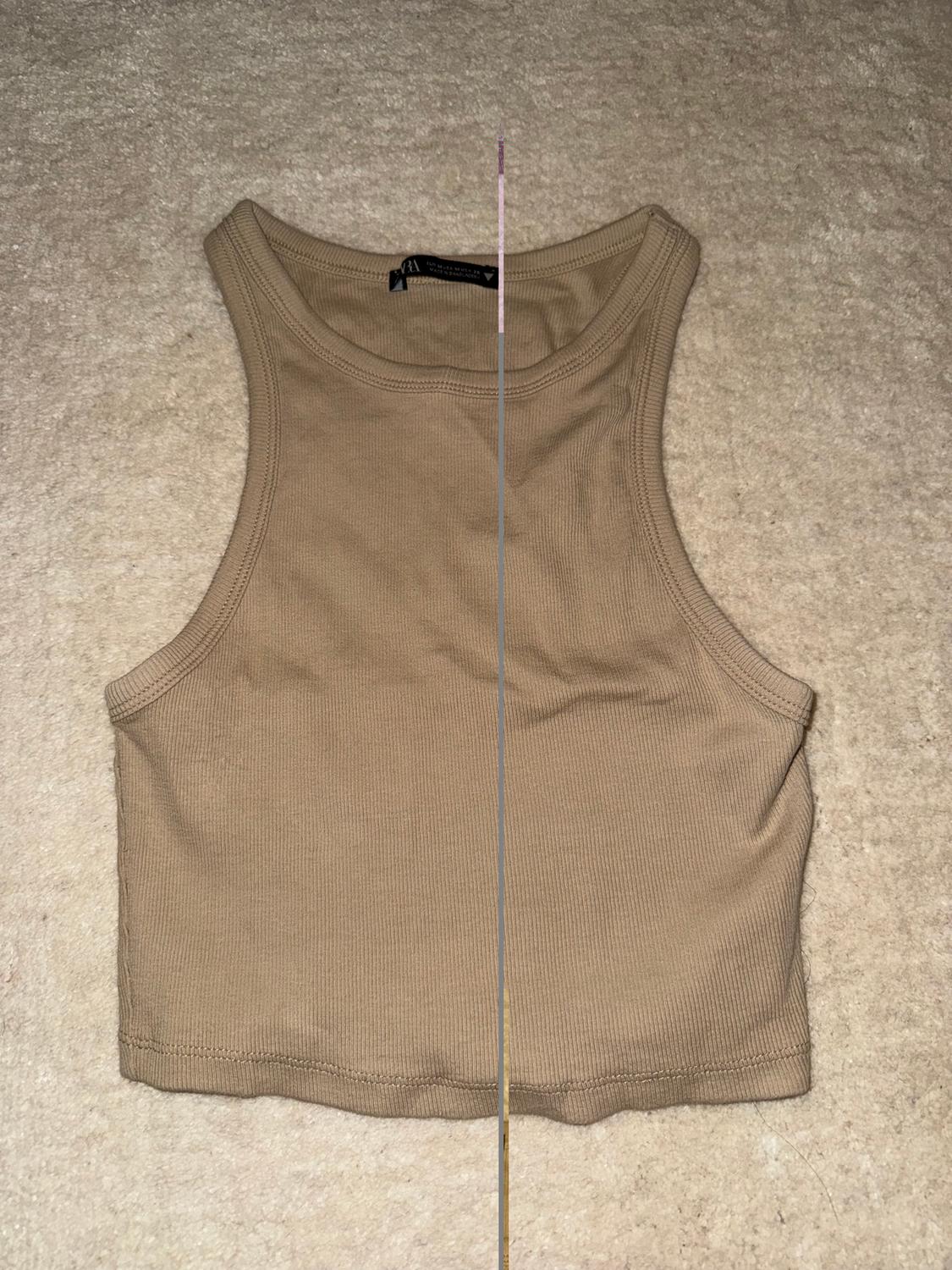 Beige sleeveless crop top on a light background. Label visible on the collar.