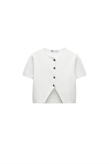 Front view of a short-sleeved white jacket with centre button fastening.