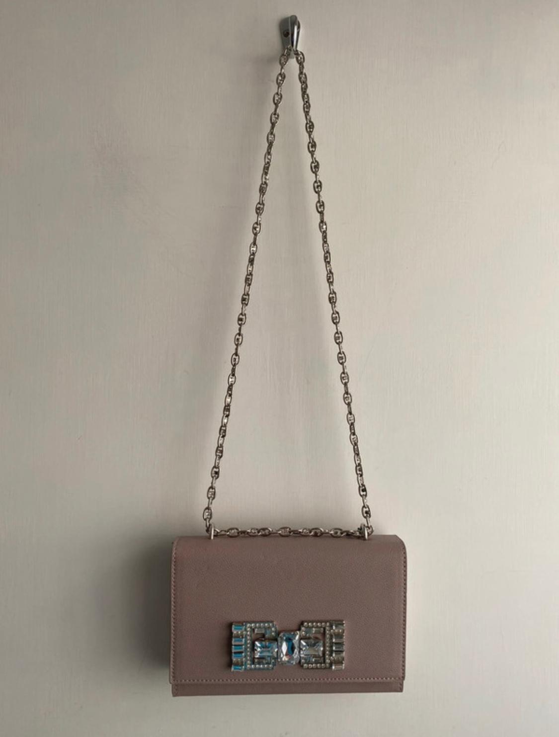 Brown bag with a chain and stone embellishment on the clasp.