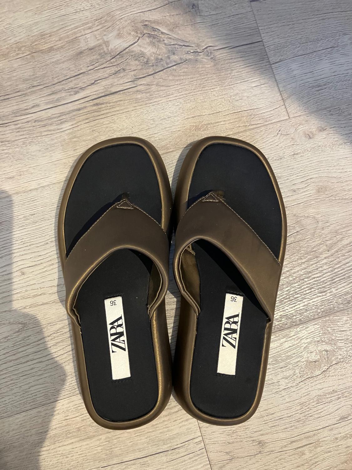 Brown toe sandals on a light wooden floor. Visible label with "ZARA" logo and size 36 on the black insole.