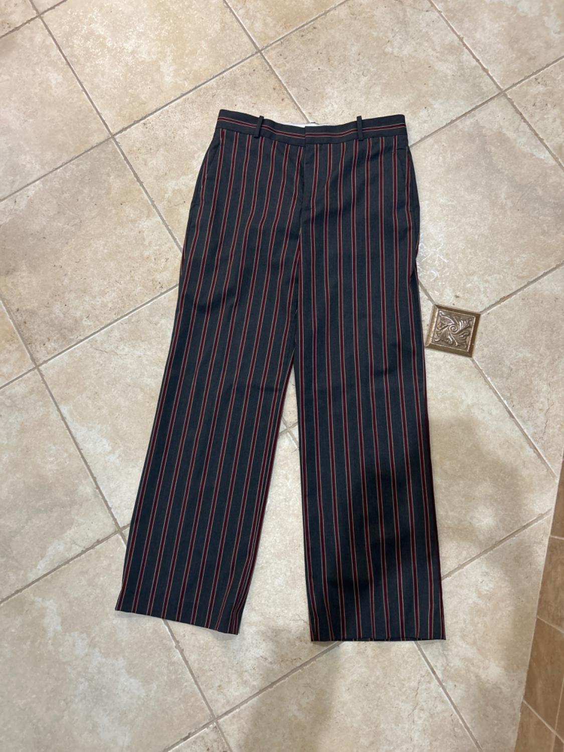 Front view of black and red vertically striped pants with side pockets and belt loops.