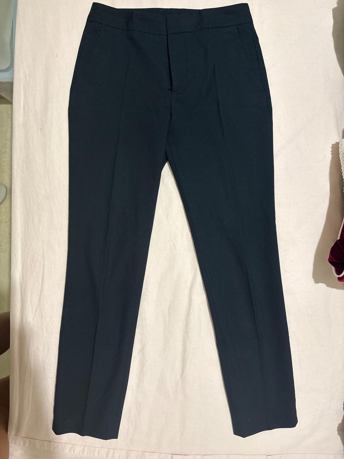 Dark smart trousers with a sharp crease, laid out on light-coloured fabric.