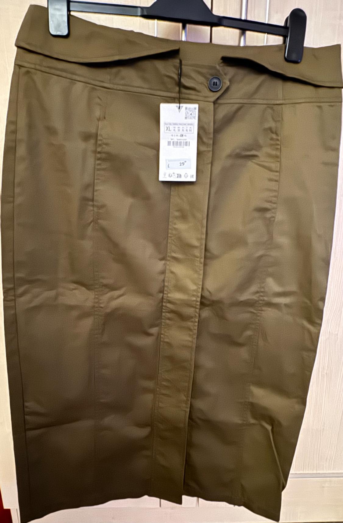 Khaki pencil skirt hanging on a black hanger, with a visible label indicating size XL and price 29.