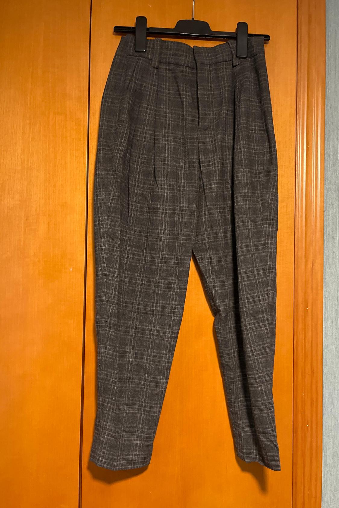 Front view of grey checked trousers with pleats and a waistband with belt loops.