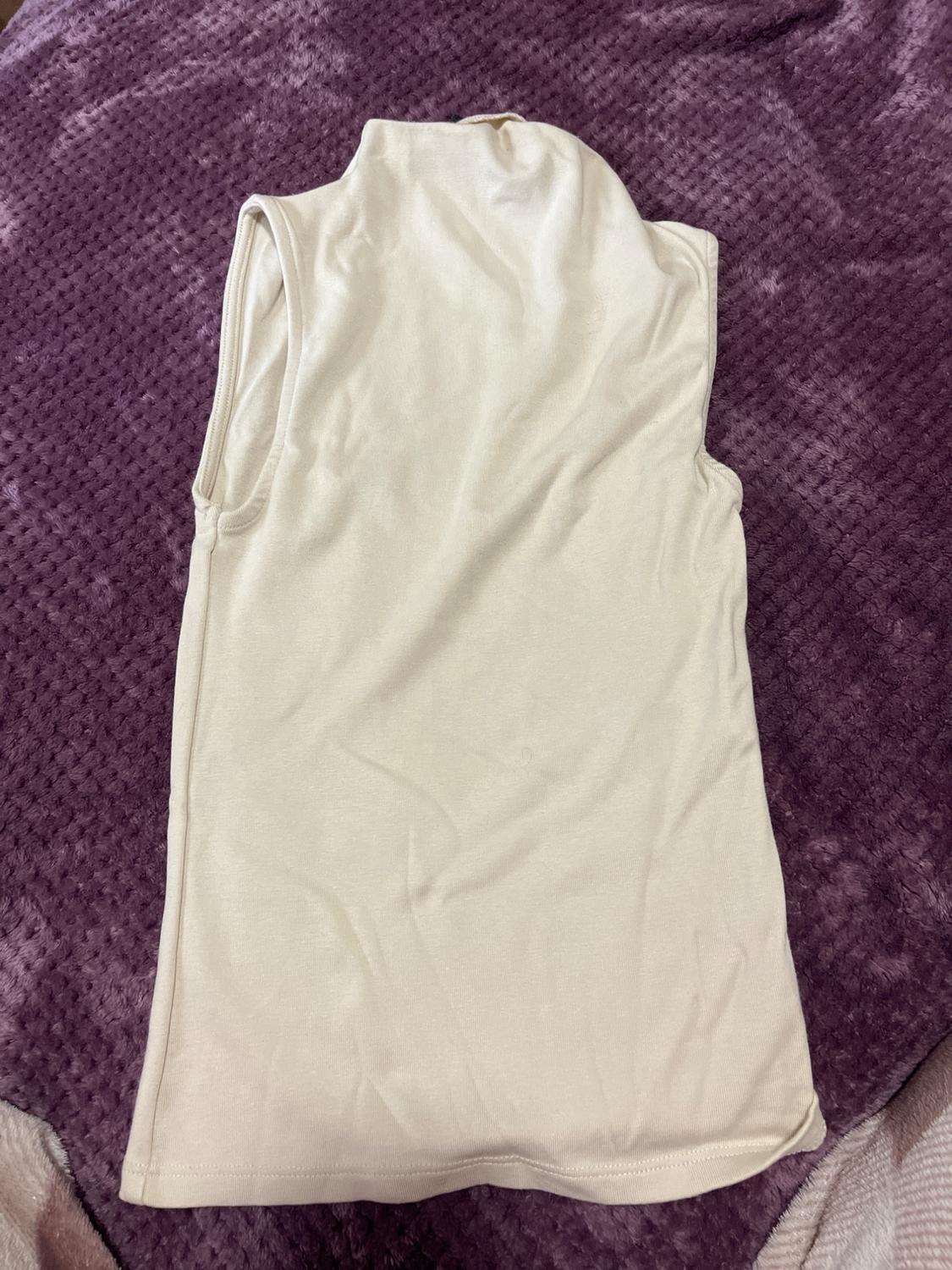 Cream-coloured vest top on a textured purple blanket.