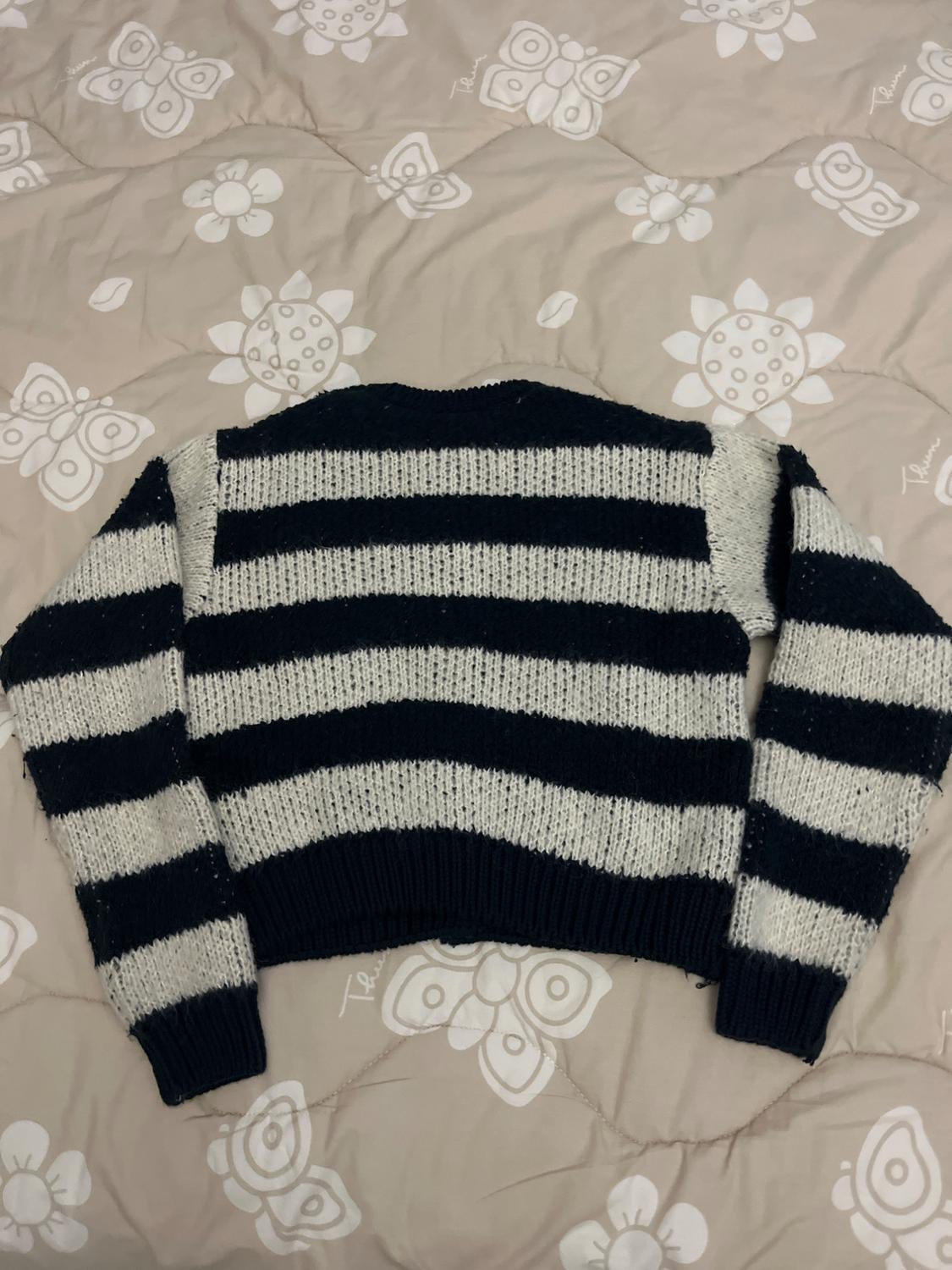 Black and white horizontal striped jumper on a beige quilt with a white floral and butterfly print.