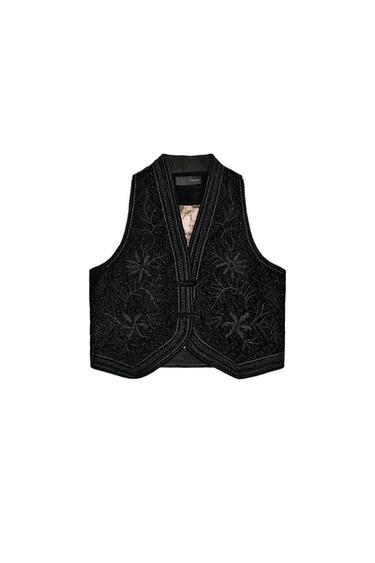 Front view of a black vest with floral embroidery and beads, a V-neckline, and a front closure.