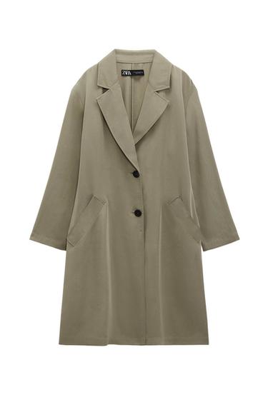 Long beige coat with wide lapels and two black buttons. Slanted pockets at the sides. Visible label on the neck.