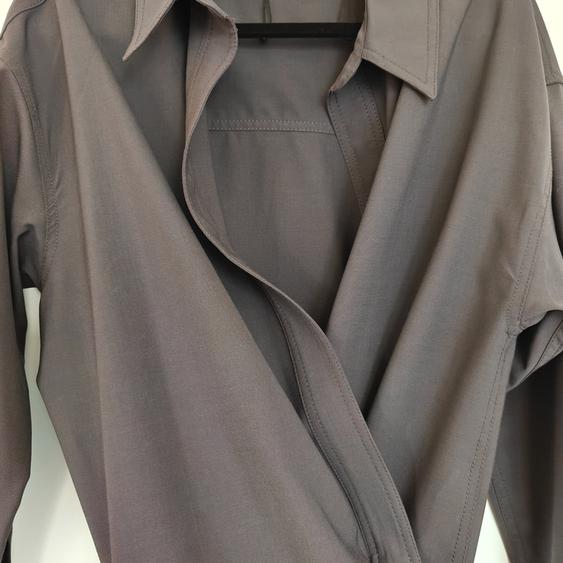 Grey long-sleeved shirt with a classic collar and crossover design, hanging on a hanger against a white background.
