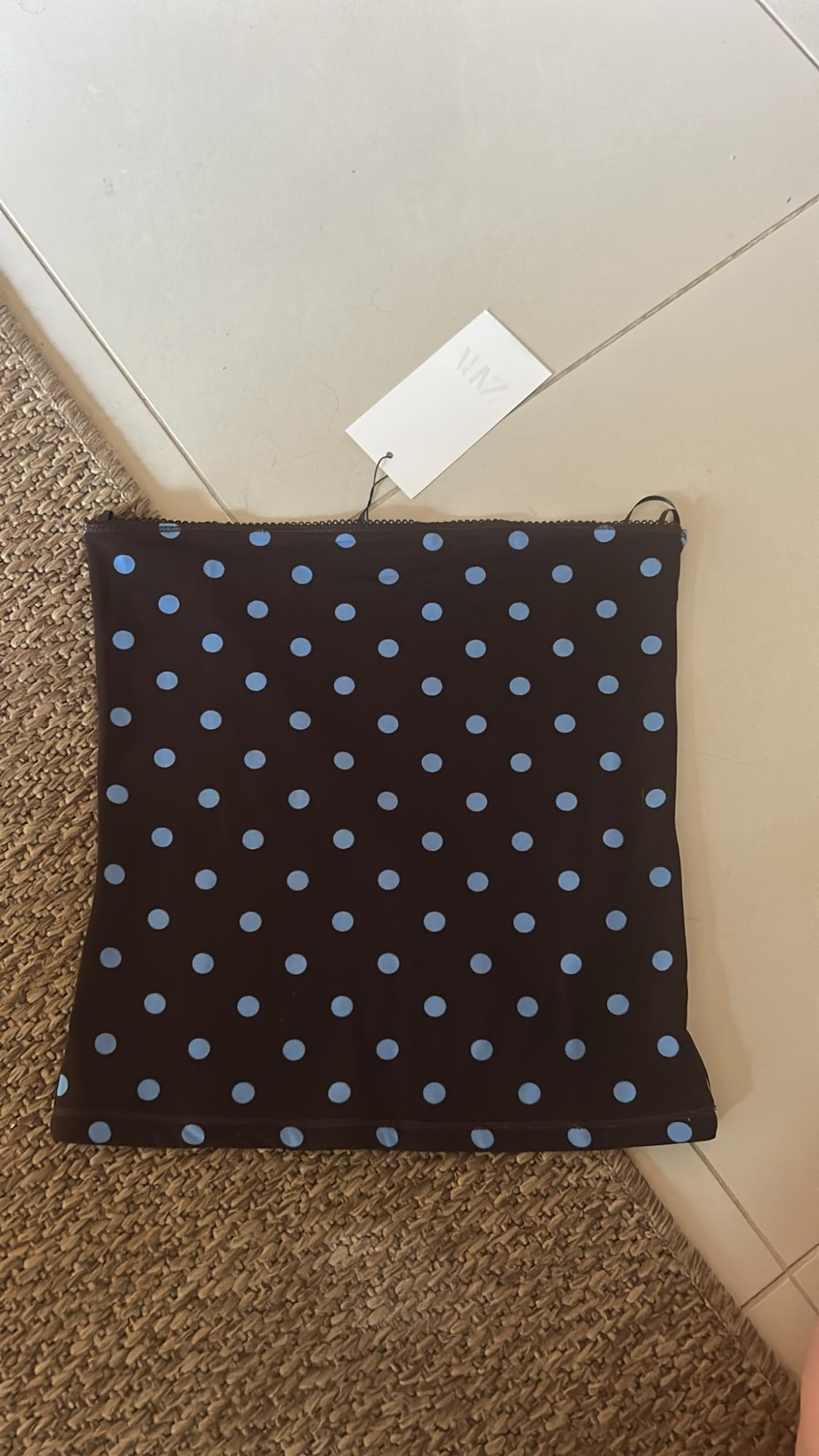 Dark top with light blue polka dots on tiles and a carpet. White label with ZARA text.
