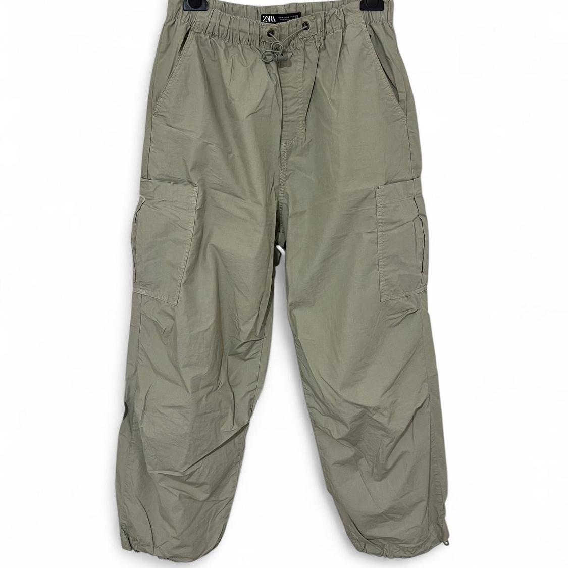 Olive green cargo trousers with side pockets and elasticated drawstring waist, hung against a white background.