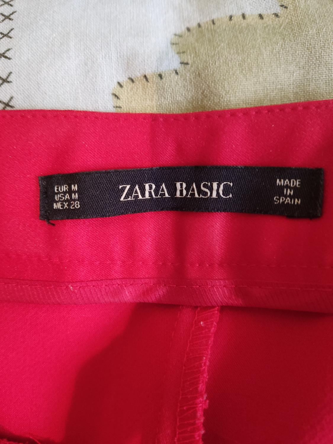 Label detail with text 'ZARA BASIC', 'MADE IN SPAIN', 'EUR M', 'USA M', 'MEX 28' on red garment.