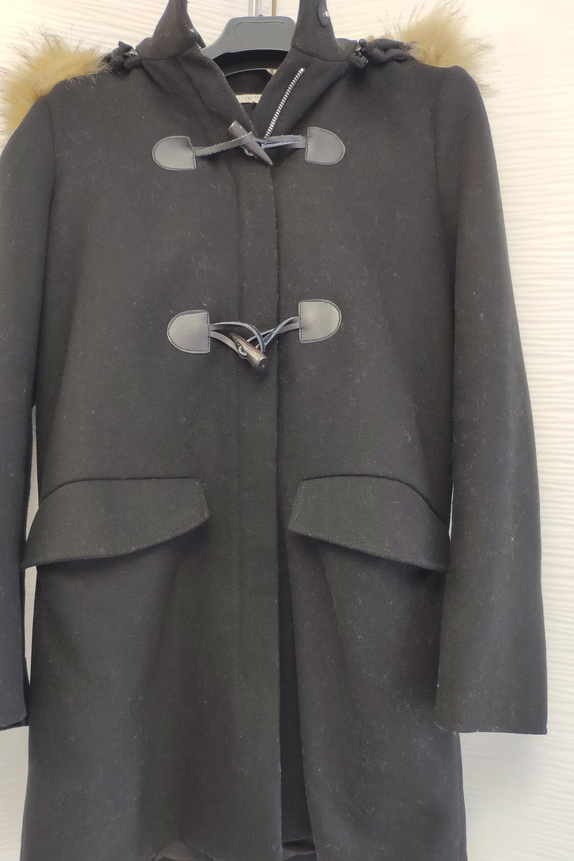 Front view of black coat with hood and toggle fastenings, front flap pockets.