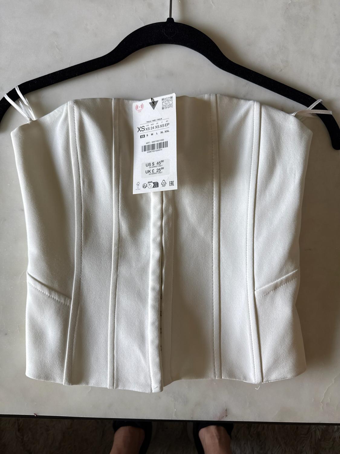 White strapless top with vertical seams on a black hanger. Label: XS XS 24 XS XS EP US $ 45.90 UK £ 25.99.