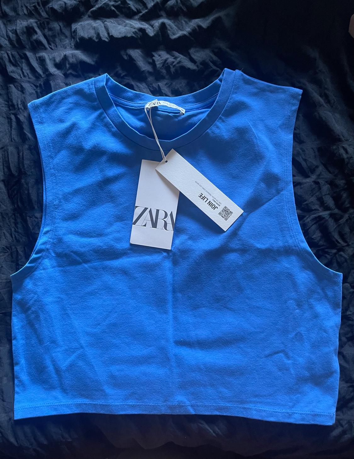 Front view of a blue sleeveless top with a visible 'ZARA' tag.