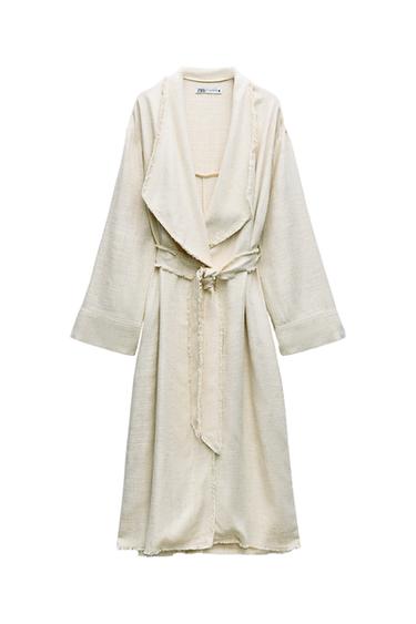 Front view of a beige coat with a belt, long sleeves, and a wide collar.
