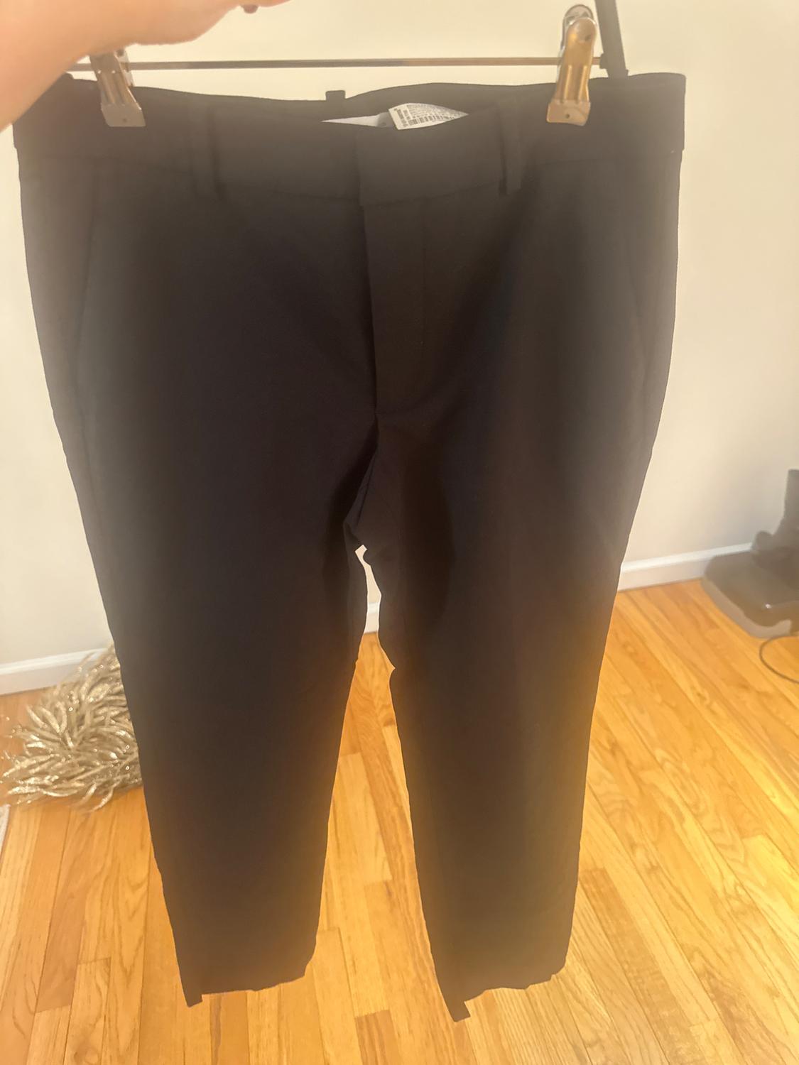 Front view of black trousers with side pockets and a front fastening.