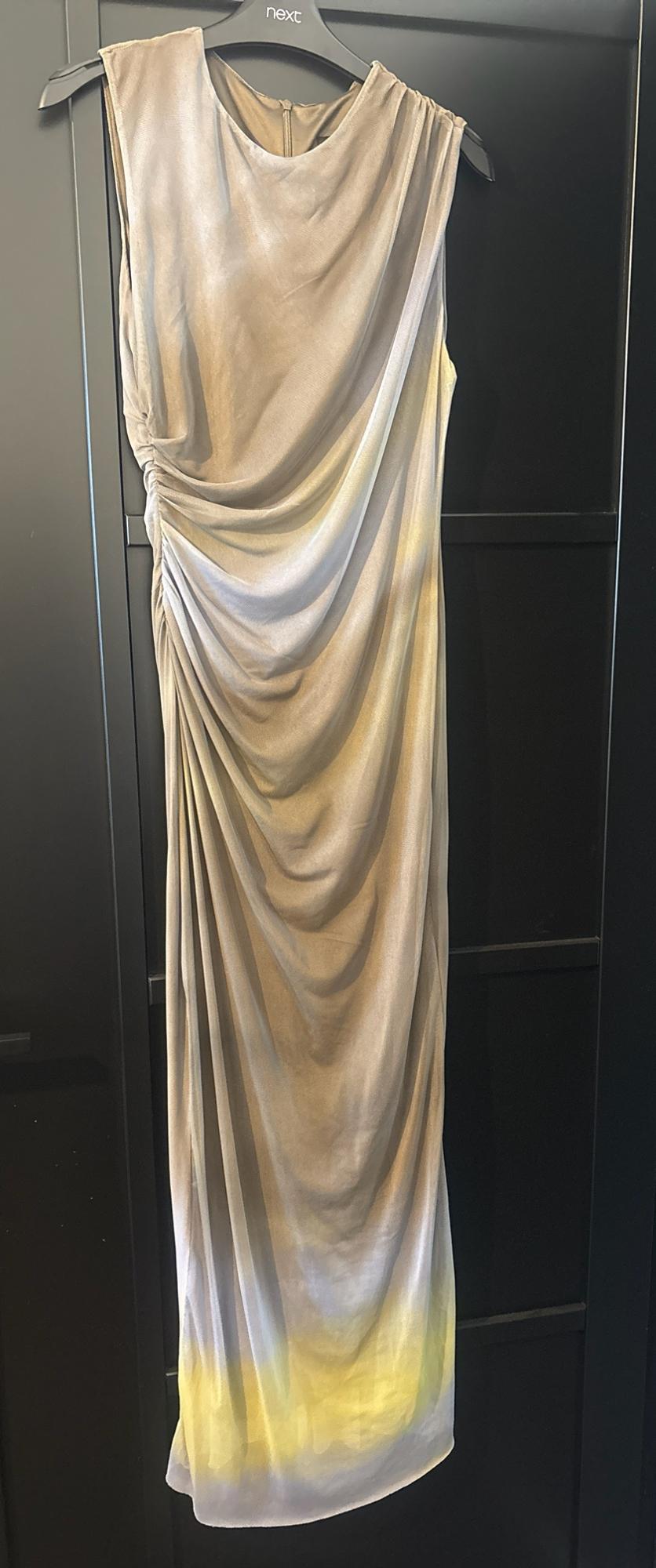Beige draped maxi dress with a blue and yellow gradient. Hanging from a hanger with the text next on a black door.