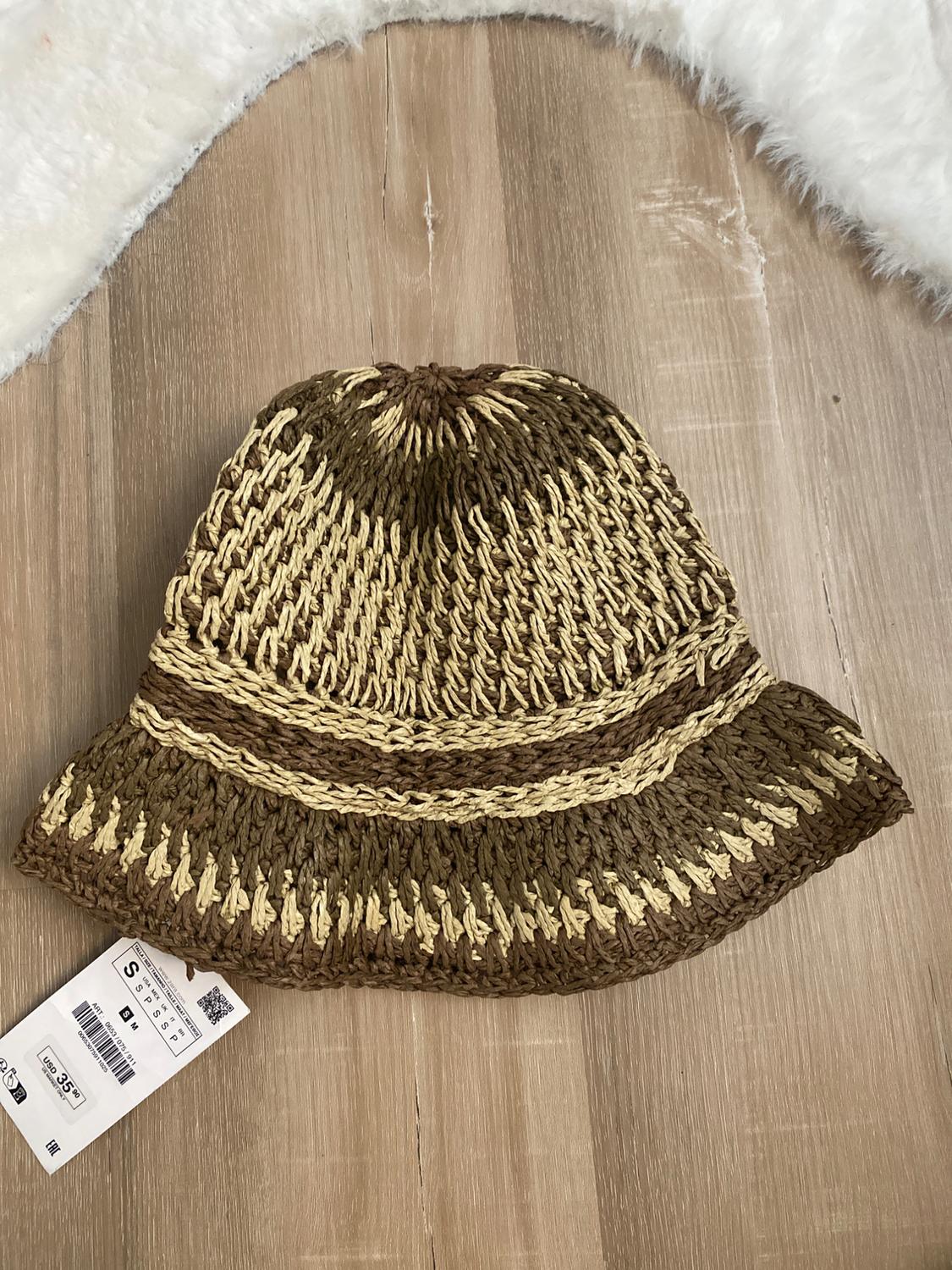 Brown and beige knit hat on a light wooden surface, with a USD 35.99 price tag attached.
