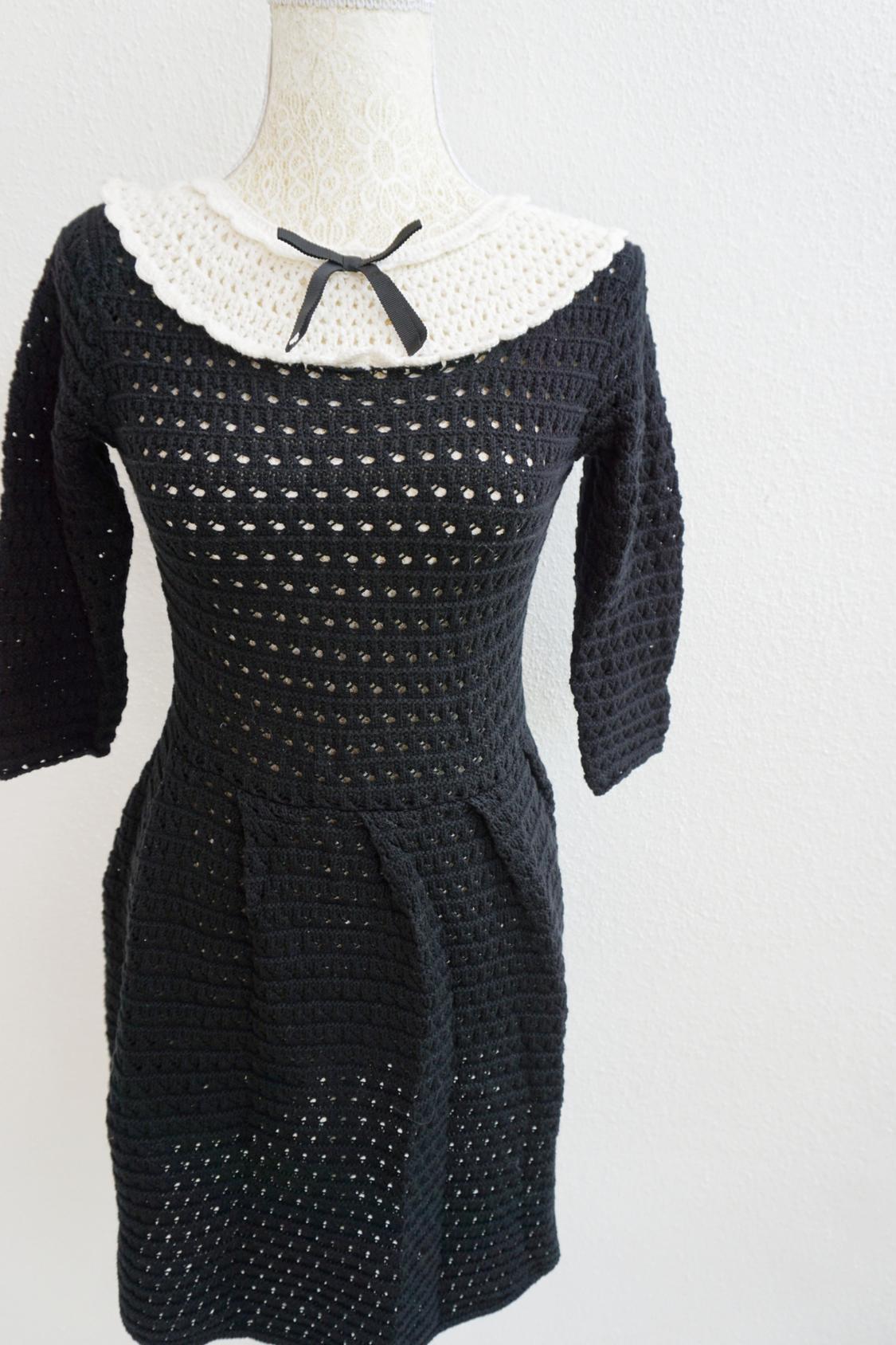 Black crochet dress with a white collar and black bow on a lace mannequin, white background.