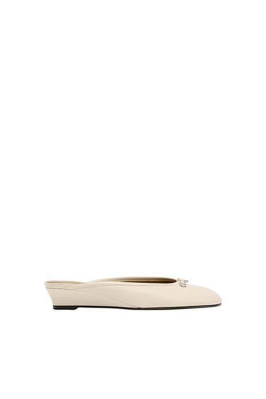 Beige slingback shoe with metallic detail on the toe and a flat sole, photographed in profile against a white background.