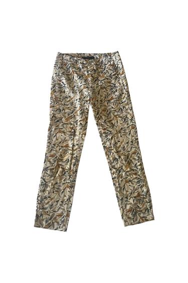 Trousers featuring a leaf print in earth tones, greys and beige on a white background.