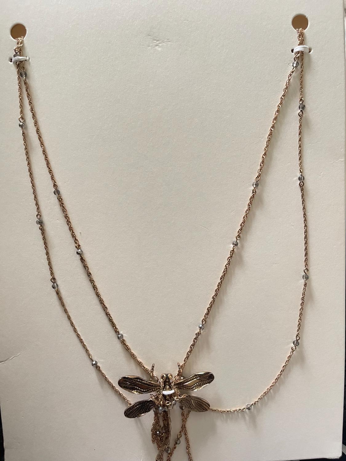 Gold necklace with dragonfly pendant and fine chains with silver-plated beads, on a white background.