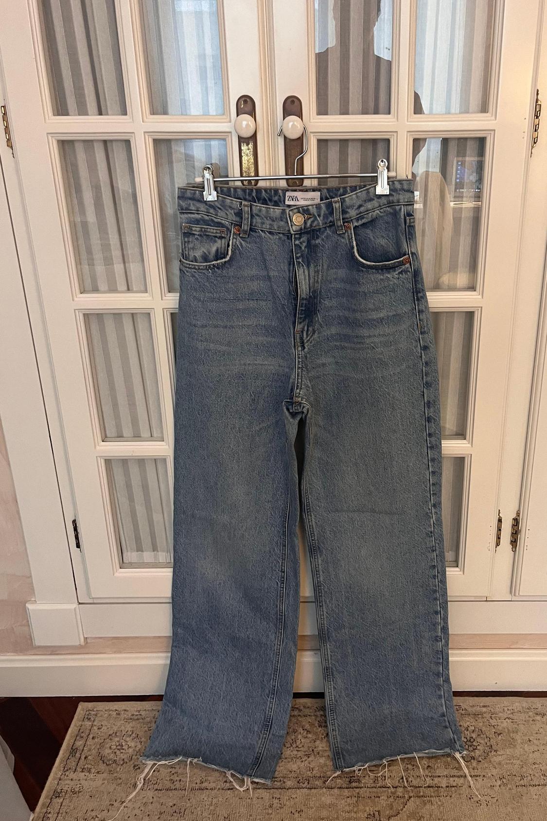 Front view of blue jeans with front pockets and frayed hems.
