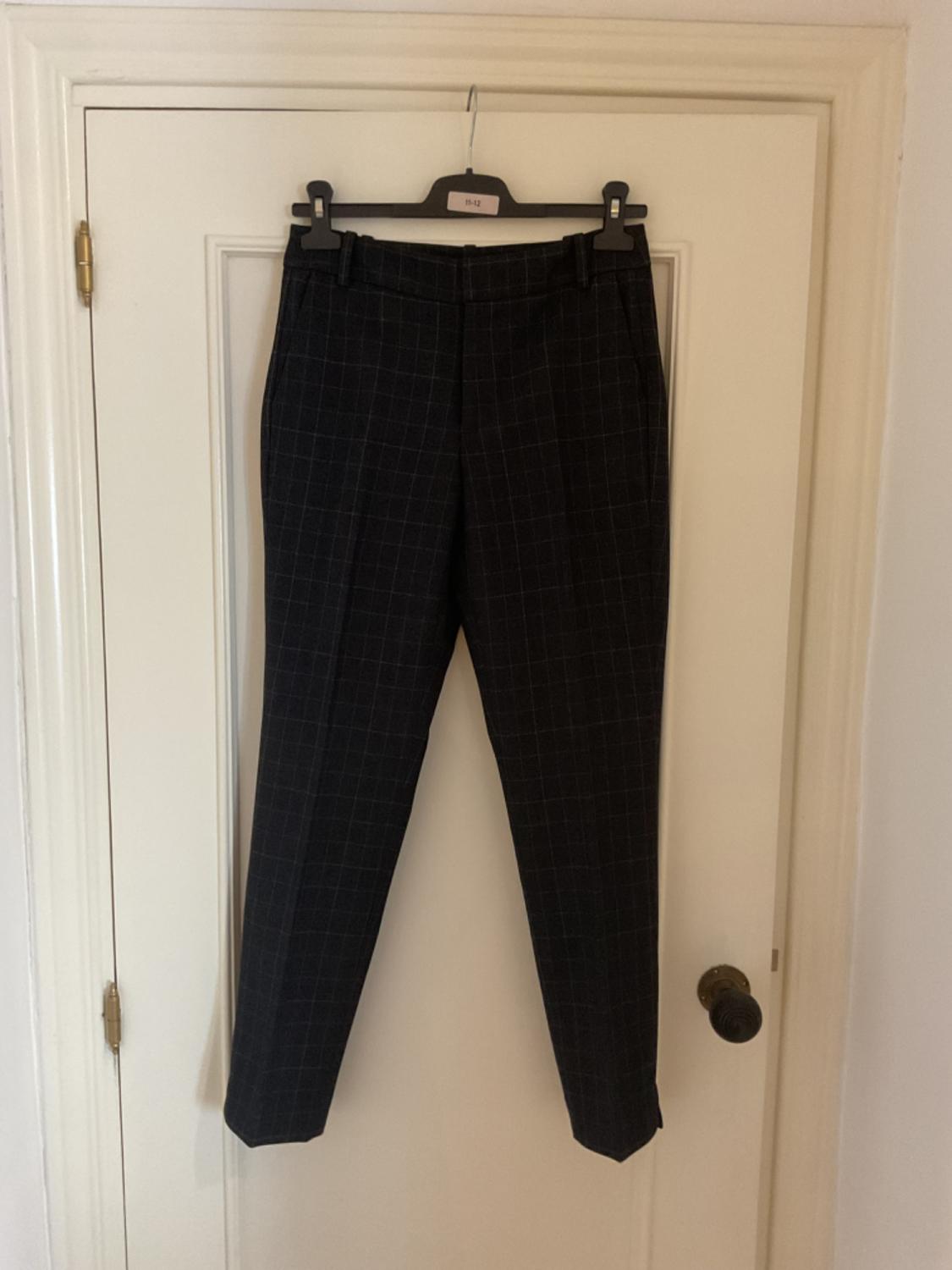 Front view of dark plaid trousers with side pockets.