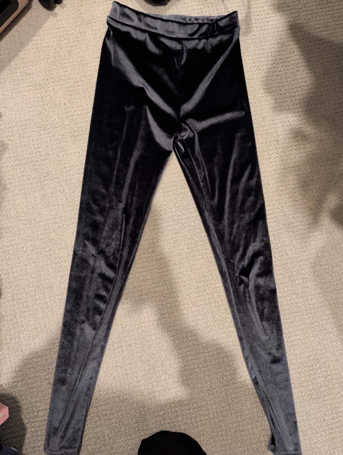 Black velvet leggings on a beige rug, illuminated by soft light.