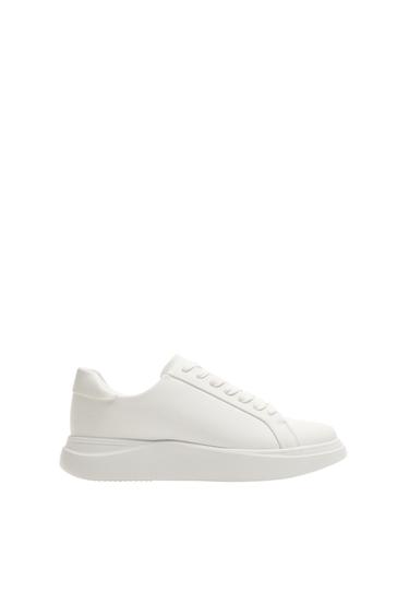 Side view of a white trainer with laces and a chunky sole.