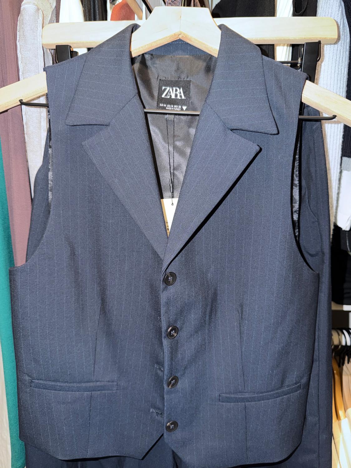 Dark blue pinstripe vest hanging on a wooden hanger, visible tag with the text "ZARA".