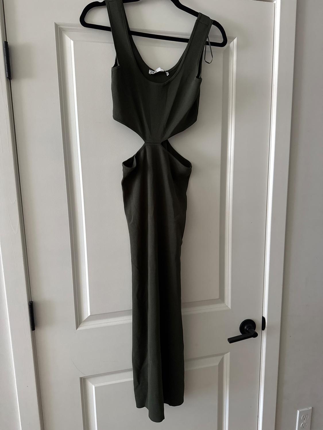 Dark green maxi dress with side slits, hanging on a black hanger over a white door.