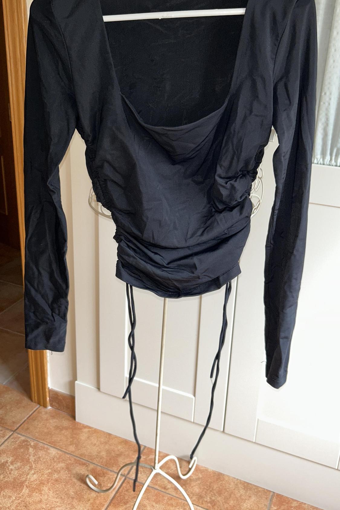 Front view of a black blouse with long sleeves and a draped neckline.