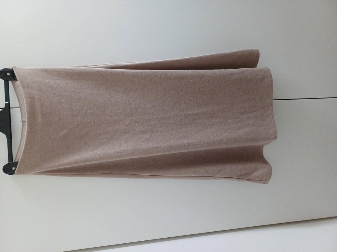 Beige skirt hanging on a black hanger against a white background. The fabric appears soft and flowing, creating a simple and elegant style.